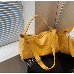 Close-up of bright yellow tote bag with Love 105 embossed text and wide strap
