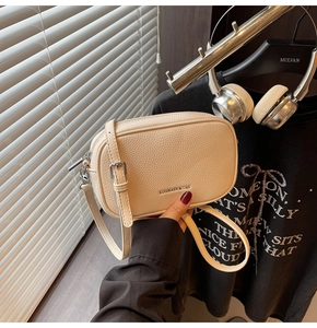 Détail du sac bandoulière beige minimaliste avec texture litchi et logo argenté