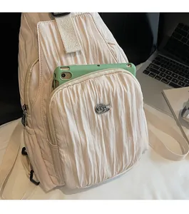 Detail of cream pleated nylon bag with hidden front zipper pocket for tablet storage