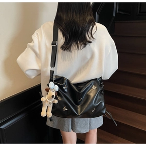 Détail du sac cabas en cuir noir avec breloques papillons argentées et pendentif chien peluche