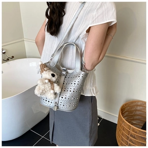 Vue détaillée d'un sac seau ajouré argenté avec un ours en peluche dans un cadre moderne