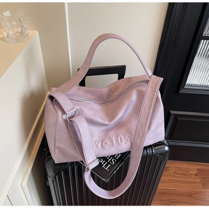 Close-up of light purple travel tote bag featuring embossed logo on a suitcase