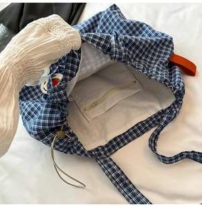 Close-up of blue plaid canvas tote bag interior with zipper pocket and lining detail