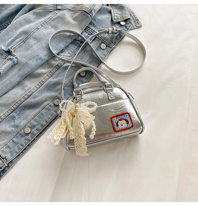 Détail du sac à main argenté avec écusson chien et nœud en dentelle et perles