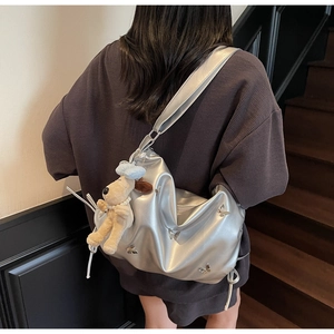 Détail du sac argenté Y2K avec breloques papillon et pendentif de chiot en peluche