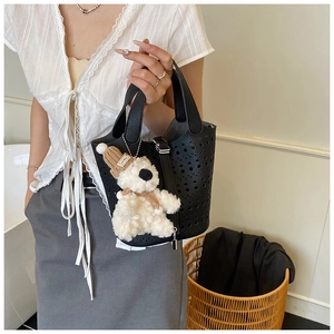 Détail d'un sac seau noir ajouré avec ferrures argentées et peluche d'ours mignon