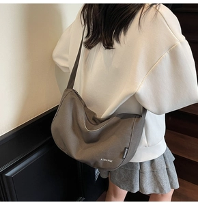 Model-Ansicht der dunklen Canvas-Tasche in Halbmondform mit breitem Schultergurt