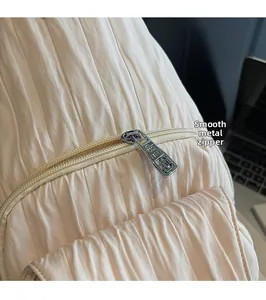 Detail of silver metal zipper and pleated fabric texture on beige backpack bag