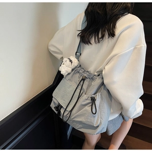 Rear view of model wearing a large grey nylon bucket bag with drawstring and pockets