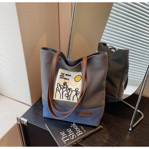 Detail of canvas and denim patchwork tote bag with brown leather shoulder straps