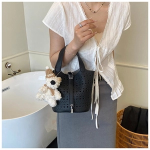 Détail du sac seau en cuir noir ajouré avec fermoir métallique et breloque ours en peluche