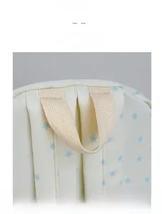 Detail view of reinforced cream webbing handle and blue star pattern on canvas backpack