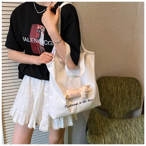 Detail of white canvas tote bag featuring 3D plush cat doll and 7 Always text print
