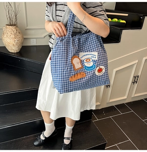 Blue and white checkered canvas tote bag with afternoon tea embroidery shown on model