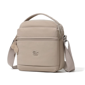Détail d'un sac bandoulière en nylon beige avec plusieurs poches zippées et logo rond
