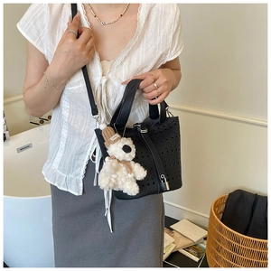 Détail du sac seau noir ajouré au laser avec un joli pendentif ours en peluche blanc