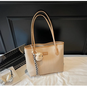 Detail of beige herringbone tote bag with brown leather trim and cute sheep charm