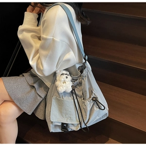 Detail of light blue nylon drawstring bucket bag with a cute white plush puppy charm