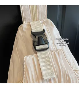 Detail of a beige crossbody bag featuring a black buckle and pleated fabric texture