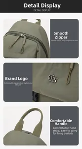 Detail view of smooth double zippers and reinforced top handle on green nylon backpack