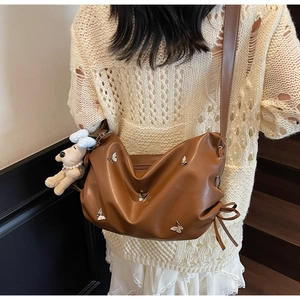 Détails du sac en cuir caramel avec papillons argentés et charme de chien en peluche