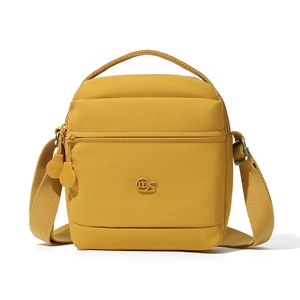 Détail du sac bandoulière en nylon jaune moutarde avec logo embossé et poche zippée