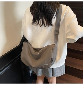 Graue Canvas-Halbmondtasche an der Schulter mit breitem Riemen und Markenetikett