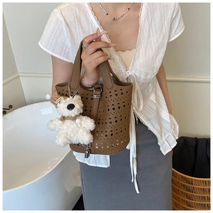 Détail du sac seau marron découpé au laser avec motifs ajourés et breloque en ours