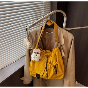Detail of yellow drawstring bucket bag with cute dog charm on a wooden hanger