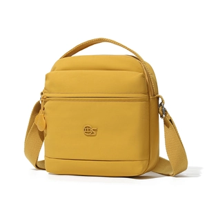 Détail du sac bandoulière en nylon jaune avec logo rond et poche avant zippée pratique
