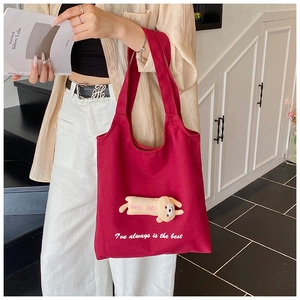 Detail of red canvas tote bag with 3D plush doll decoration and large capacity