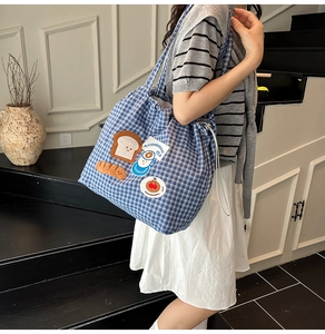 Close-up of blue checkered canvas tote bag with cartoon food embroidery and drawstring