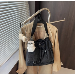 Detail of black nylon drawstring crossbody bag with side pockets and teddy charm