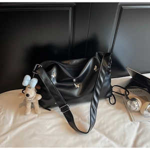 Détail du sac bandoulière en cuir souple noir avec papillons et charm de chien