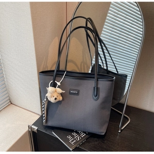 Detail of dark grey tote bag with textured surface and cute white plush bear charm