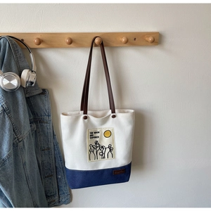 Close-up of contrast canvas tote bag with leather strap and moon embroidery detail