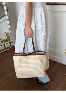 Close-up of yellow striped canvas tote bag with brown leather handles and interior lining