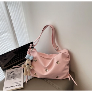 Détail du sac rose avec breloques papillon dorées et un pendentif chien en peluche