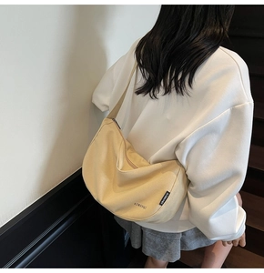 Detailaufnahme der beigen Canvas-Umhängetasche mit dem AIMANQI-Markenlogo für Damen