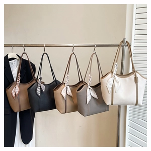 Row of large leather tote bags with floral scarves on handles in various colors