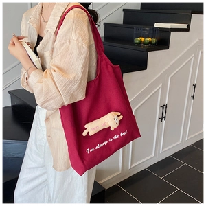 Close-up of burgundy canvas tote featuring cute 3D cat patch and white text embroidery