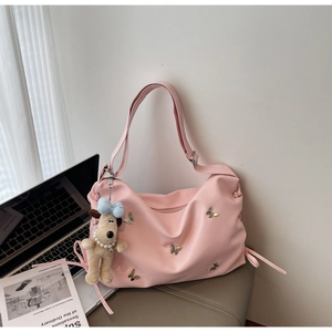 Détail du sac hobo rose avec papillon doré et breloque chien peluche sur siège doux