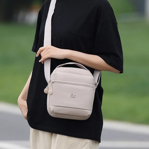 Sac bandoulière beige tendance porté à l'extérieur avec une large sangle réglable