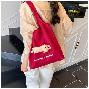 Red canvas tote bag with 3D plush doll detail shown as shoulder bag style on a model