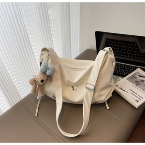 Détail d'un sac beige avec décoration papillon argentée et pendentif chien peluche