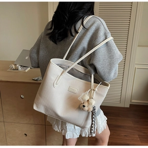 Detail of white PU leather tote with woven texture and cute plush bear charm