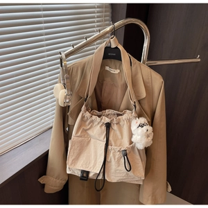 Detail of beige canvas drawstring bag with multi-pocket design and plush puppy pendant