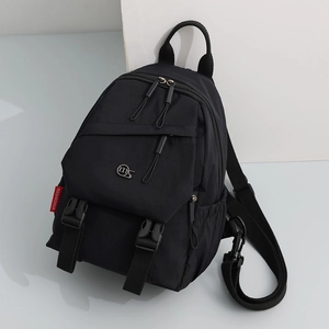 Detail view of black nylon backpack with durable zipper pockets and metal logo badge