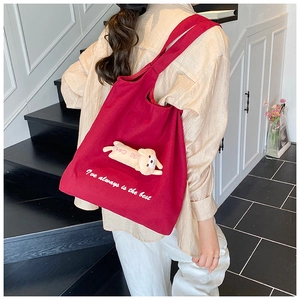 Detail of red canvas tote bag with 3D plush cat pendant and white text embroidery