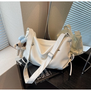 Détail d'un sac hobo blanc en cuir avec charms papillons et pendentif chiot peluche